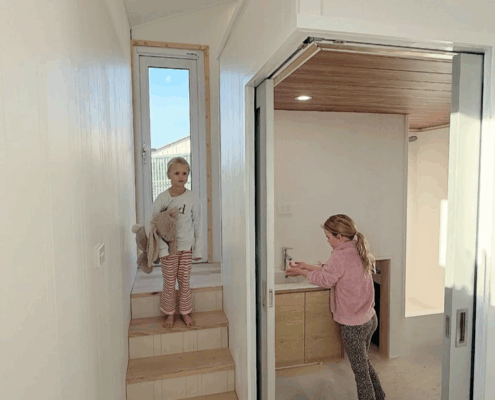 TCs kids 1 Two girls playing inside a Nexus Communities modular home, part of a social impact housing project in Australia